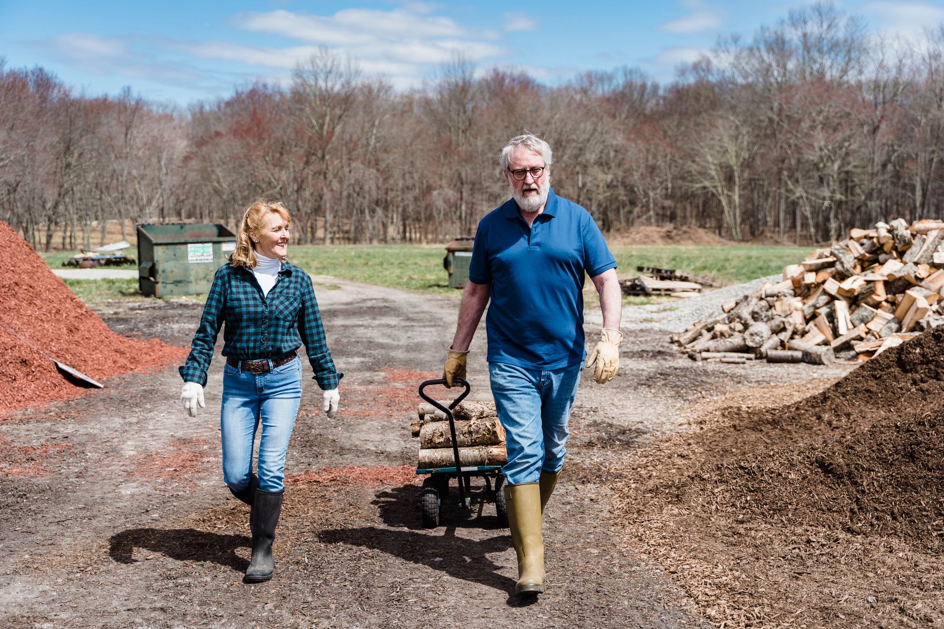 A couple spreading mulch with a wheelbarrow in a garden