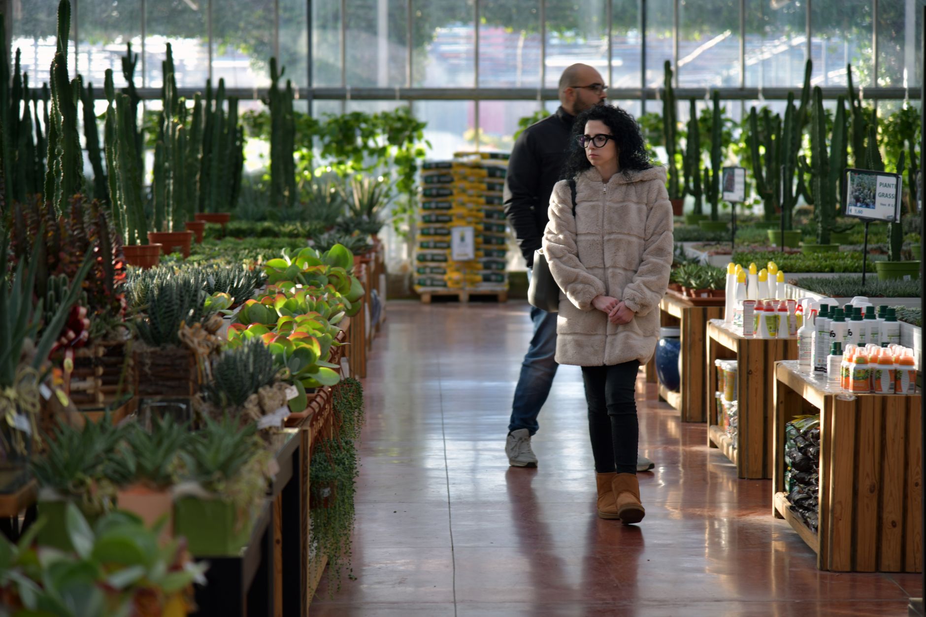 Shoppers browsing plants and gardening supplies in a well-lit indoor garden center
