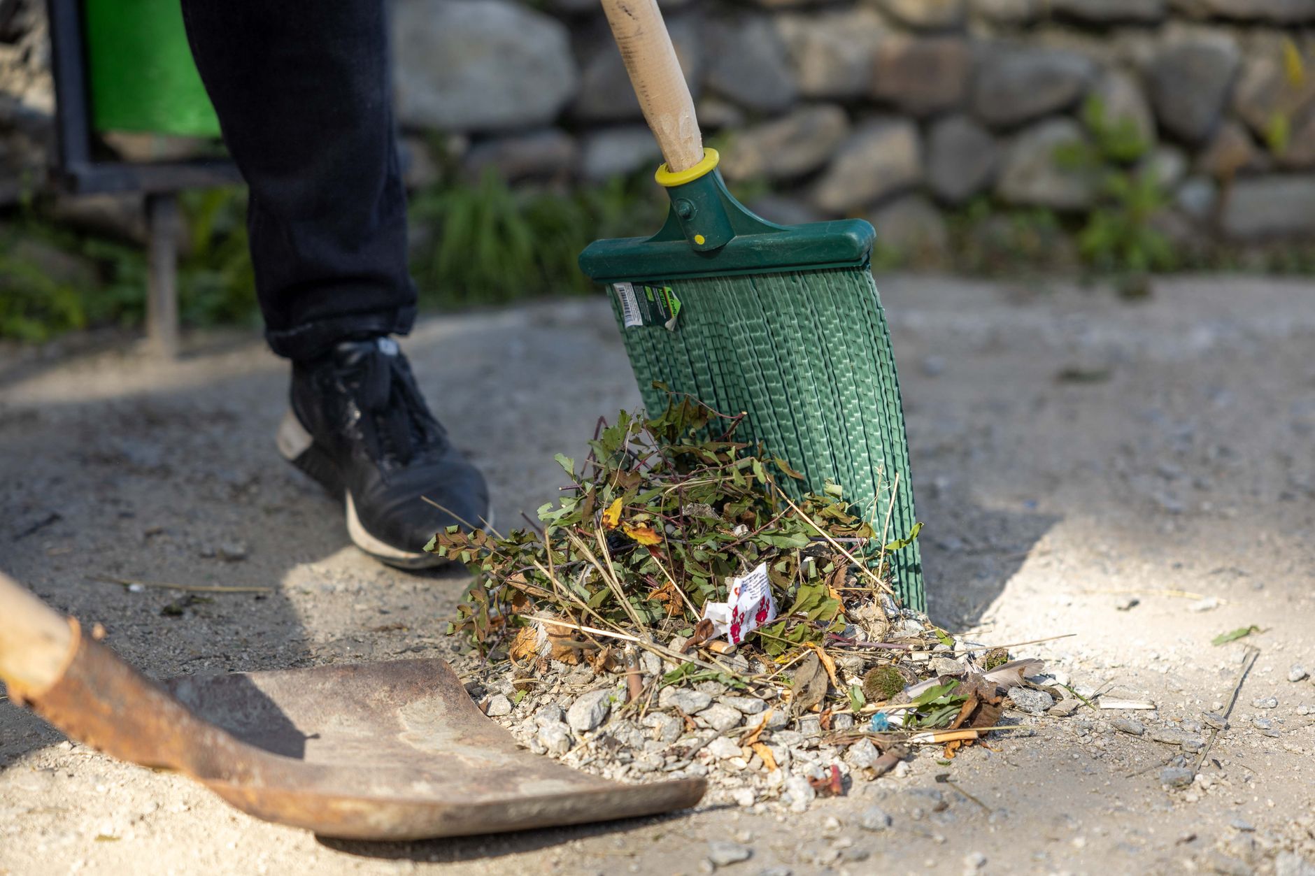 Close-up of a person raking leaves and debris in a yard